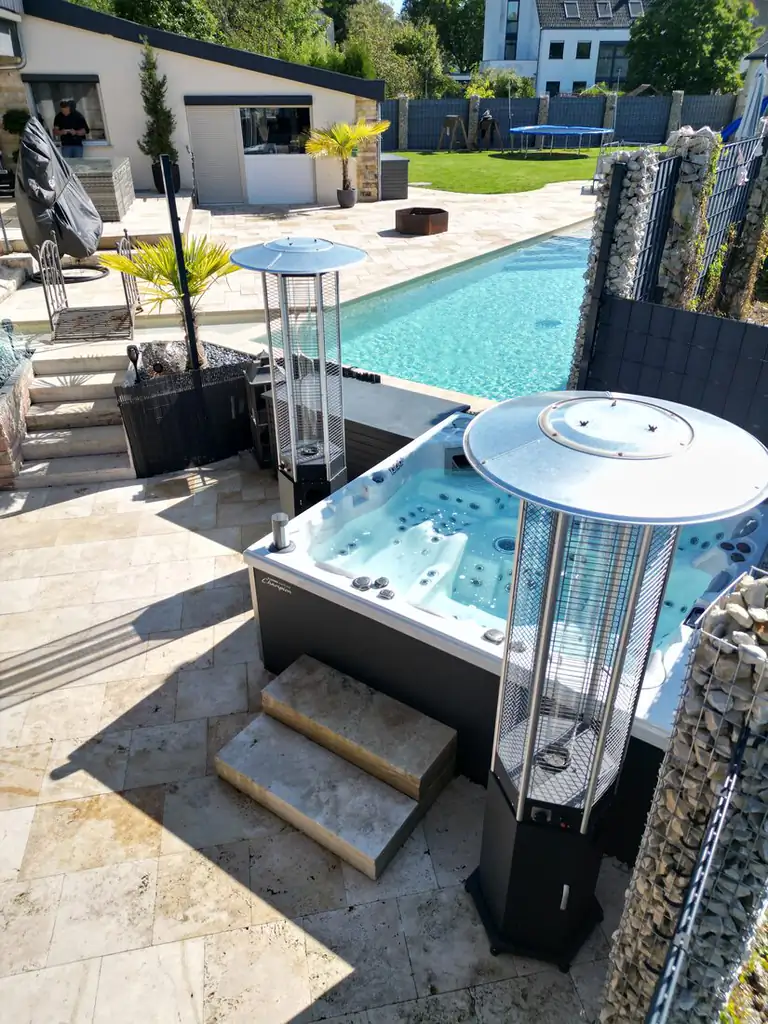 Whirlpool mit Holzstufen auf der Travertinterrasse neben dem Pool, mit Terrassenheizstrahlern