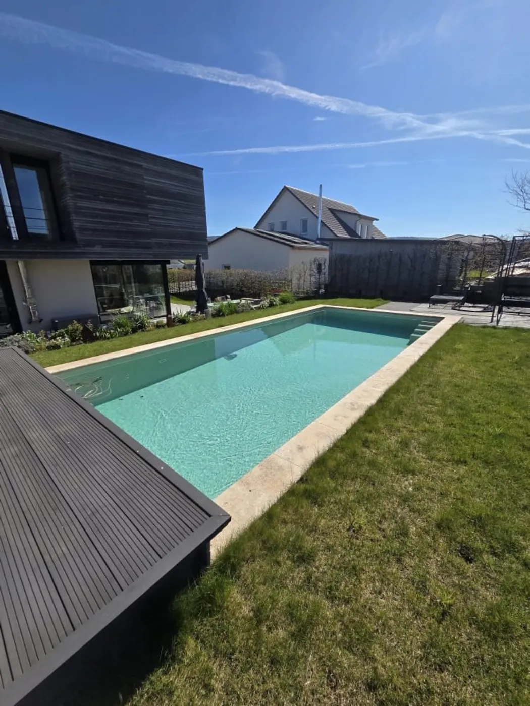Langgestrecktes Sportbecken am Neubau mit dunklem Holzdeck