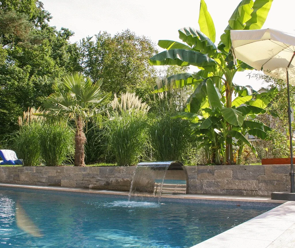Palmen und Bananenstauden hinter dem Pool mit Wasserfall in Villingen-Schwenningen