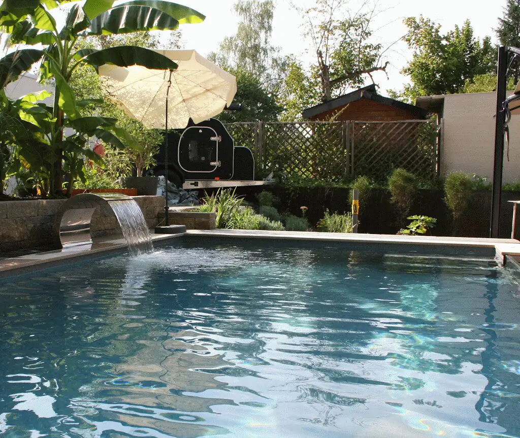 Wasserfall und Bananenstaude mit Sonnenschirm hinter dem Pool in Villingen-Schwenningen