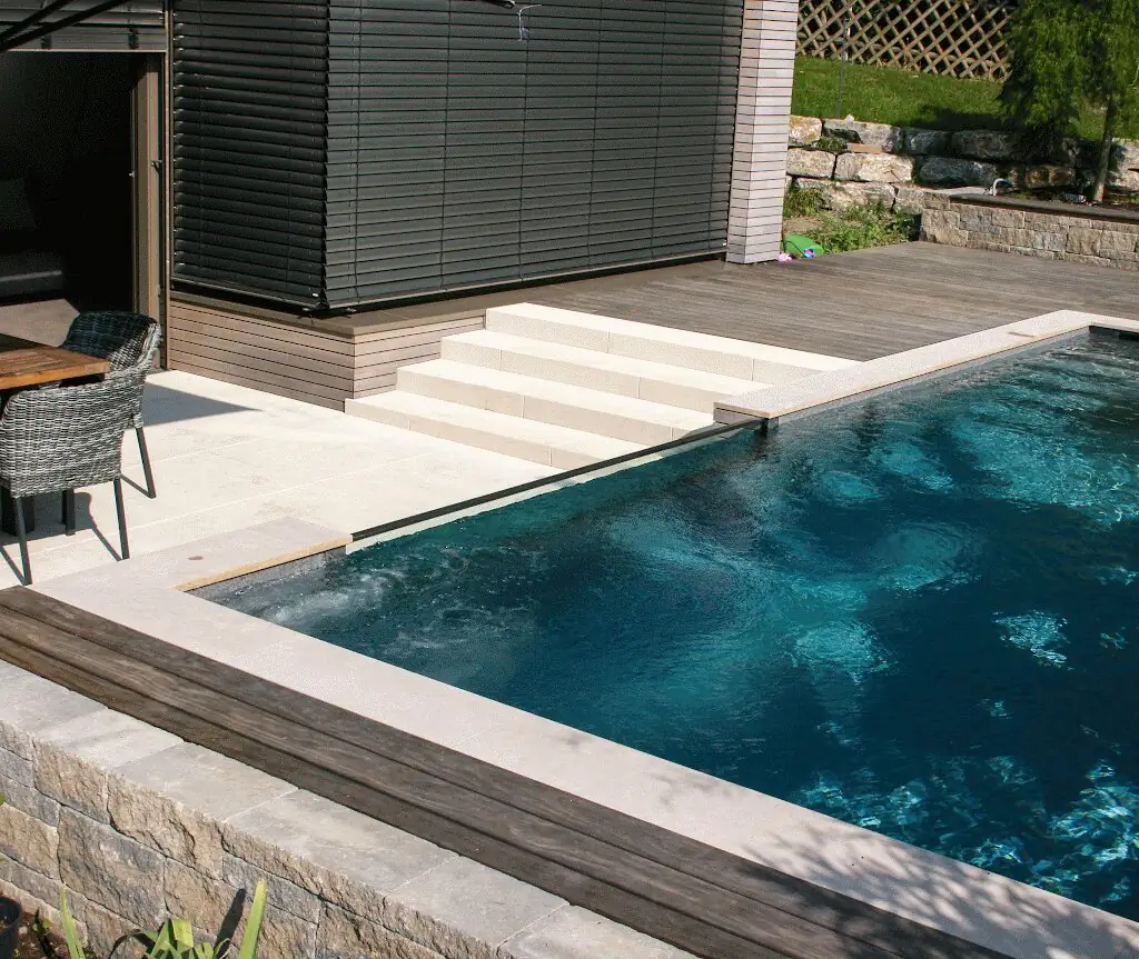 Pool mit Natursteinkante und Holztreppe vor dem Wohnhaus in Villingen-Schwenningen