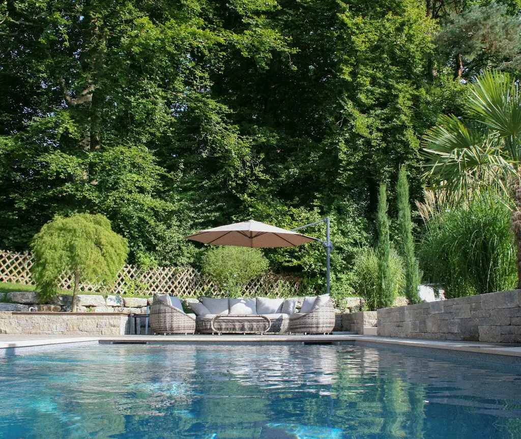 Pool mit Lounge und Natursteinmauer, dahinter der Garten in Villingen-Schwenningen