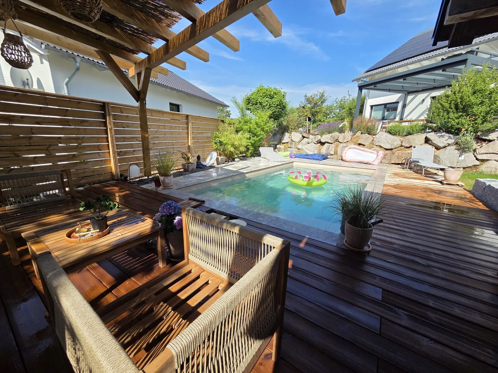 Loungebereich auf dem Holzdeck mit Blick auf Pool und Natursteinmauer in Villingen-Schwenningen
