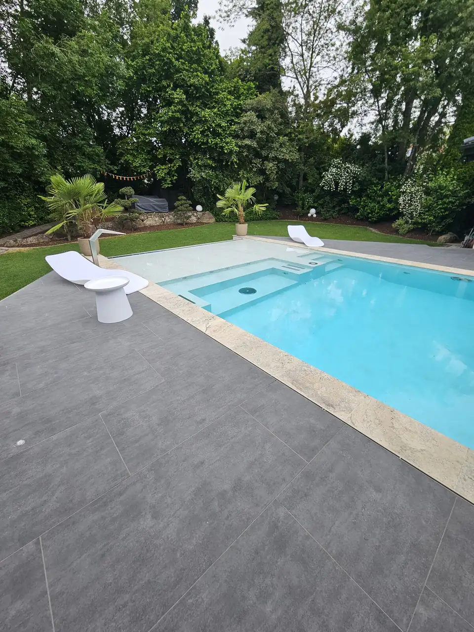 Pool mit Einstiegsstufen und weißen Liegen vor dem Garten in Villingen-Schwenningen