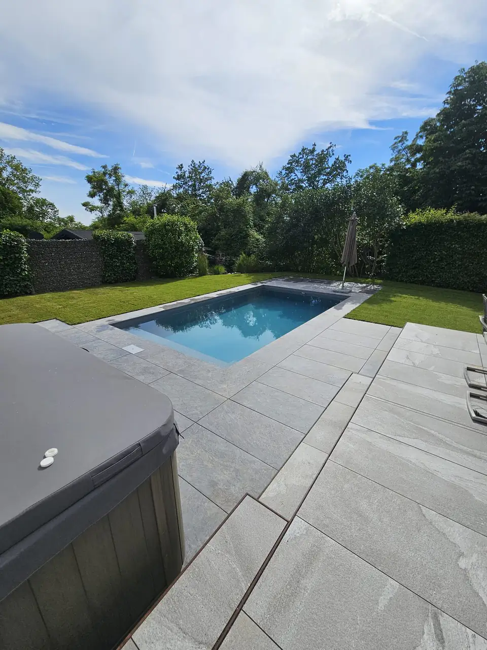 Pool mit dunkler Wasserfläche und Großformat-Terrasse neben dem Whirlpool in Villingen-Schwenningen